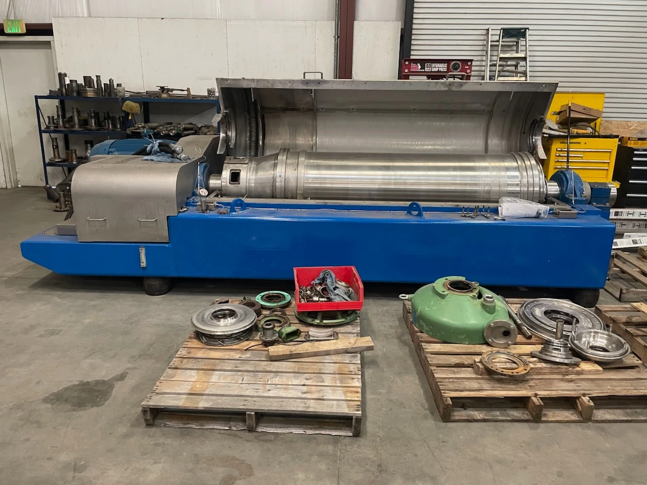 Decanter centrifuge opened for teardown and inspection with rebuilt parts staged on pallets at Sully Enterprises